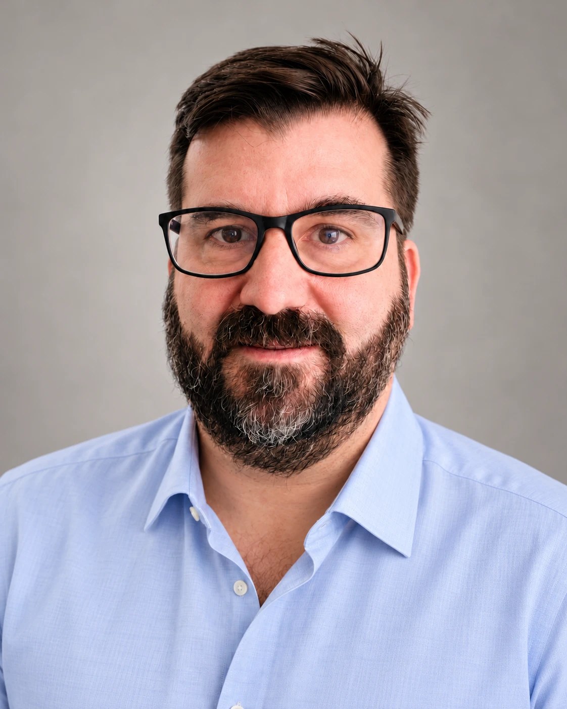 Stefan Mayer, Inhaber von MES, mit Brille und hellblauem Hemd vor grauem Hintergrund.